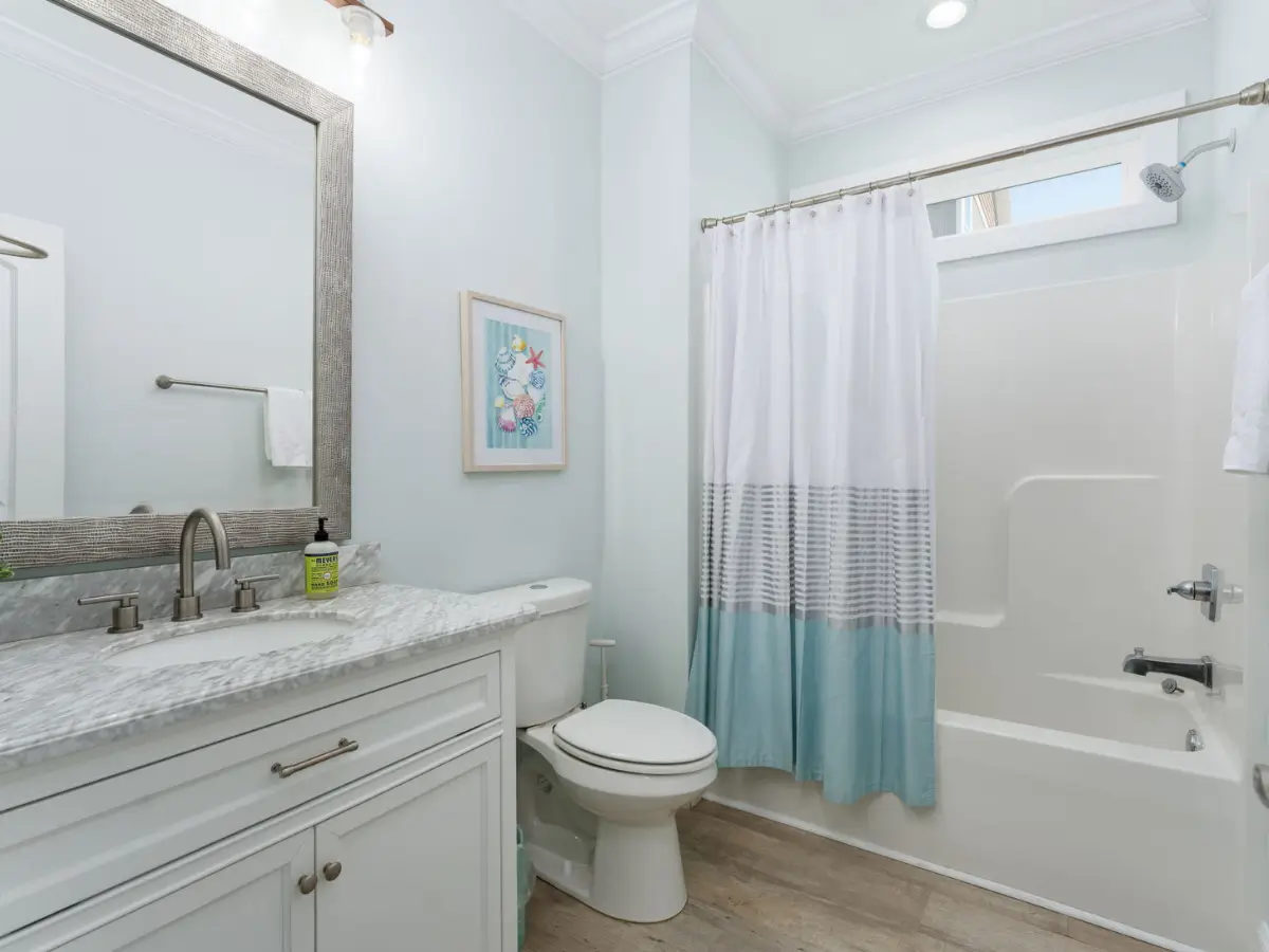 Clean guest bathroom with marble vanity and full bathtub at A Sail Away vacation rental.