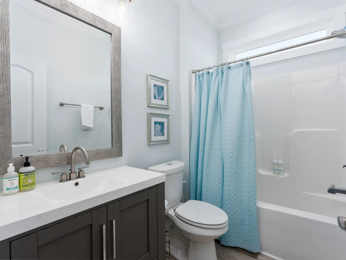Bright full bathroom with modern vanity and bathtub at A Sail Away beach house.