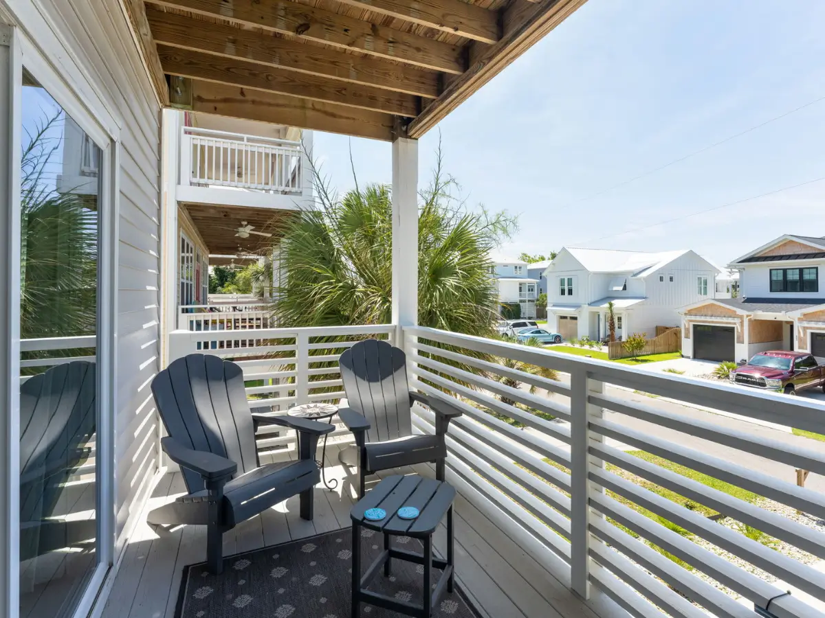 Private covered balcony with Adirondack chairs at A Sail Away vacation rental in Carolina Beach.