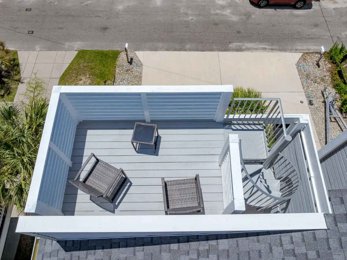 Covered upper balcony with seating and spiral staircase leading to rooftop deck in Carolina Beach.