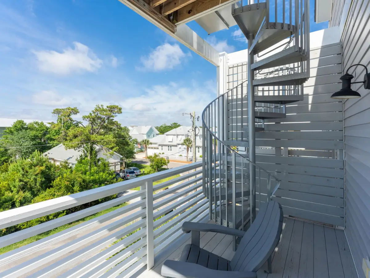 Covered upper balcony with seating and spiral staircase leading to rooftop deck in Carolina Beach.