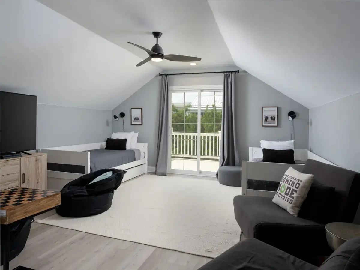 Large upstairs loft with twin beds, gaming lounge, and private balcony access.