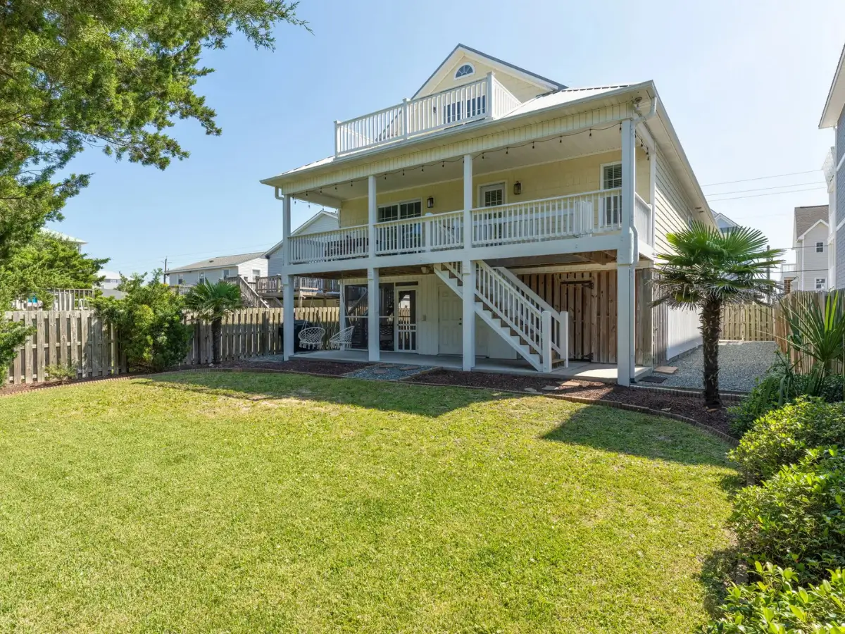Backyard view of Salty Dream featuring a large covered porch, spacious lawn, and outdoor living area.
