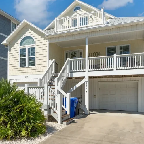 Front exterior of the Salty Dream vacation rental in Ocean Isle Beach, NC with covered porch and elevated coastal home design.